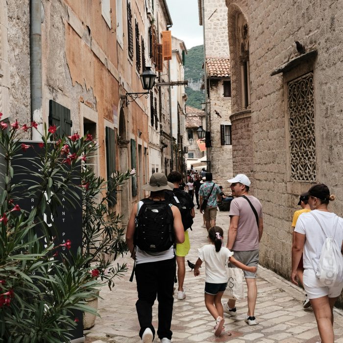 Tourists walk through cobblestone streets of Kotor, Montenegro, capturing an old town charm.