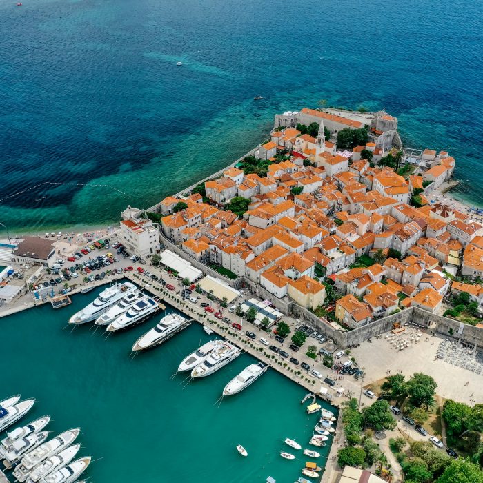 A stunning aerial shot of a European old town by the coast with a marina filled with yachts.